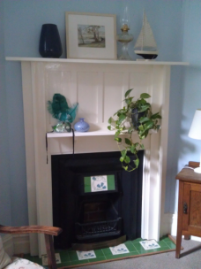 The fireplace holds a collection of little things including an antique painting